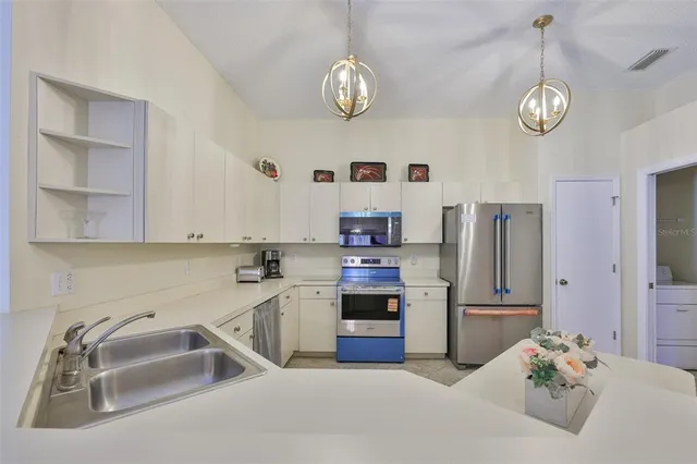 a kitchen with stainless steel appliances granite countertop a sink dishwasher stove and refrigerator with wooden floor