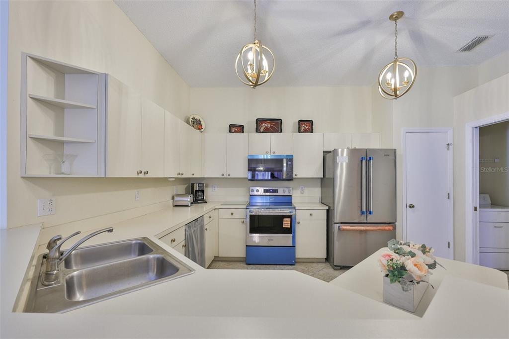 2431 Nantucket Harbor Loop, Unit 61 Sun City Center, FL 33573 - Photo 12 of 37 a kitchen with stainless steel appliances granite countertop a sink dishwasher stove and refrigerator with wooden floor