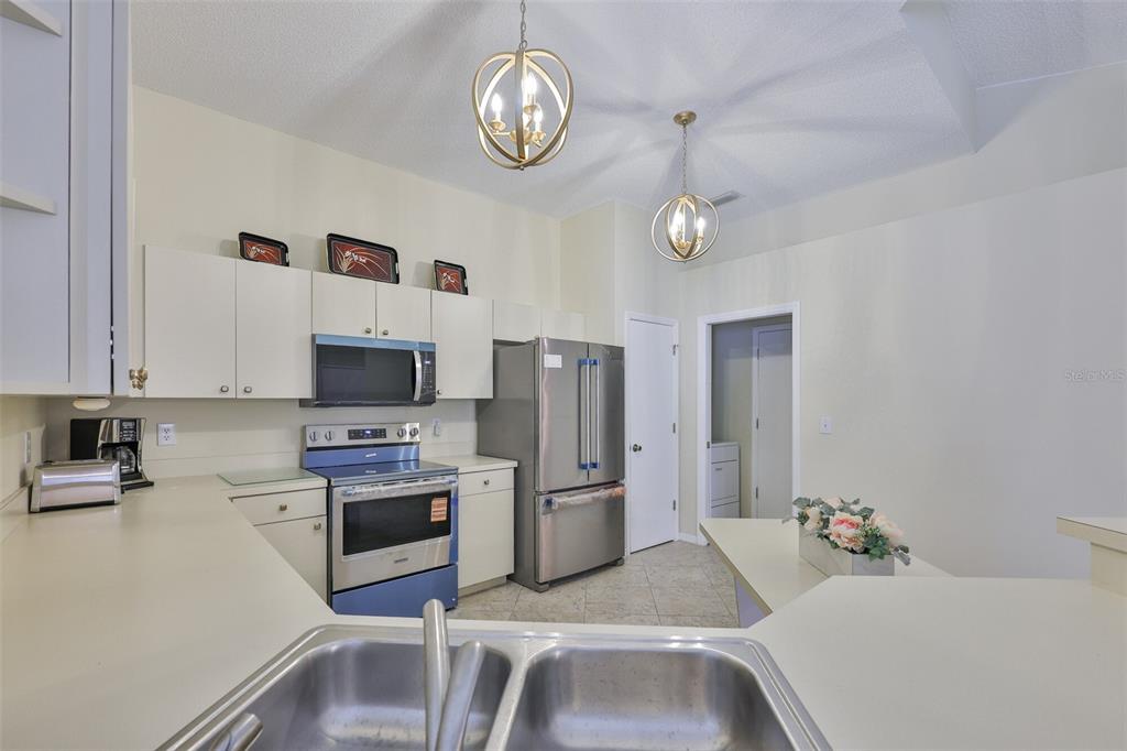 2431 Nantucket Harbor Loop, Unit 61 Sun City Center, FL 33573 - Photo 13 of 37 a kitchen with stainless steel appliances granite countertop a refrigerator a stove oven a sink dishwasher and white cabinets with wooden floor