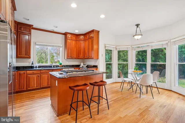 a kitchen with stainless steel appliances granite countertop a stove a refrigerator a sink dishwasher with a dining table and chairs with wooden floor