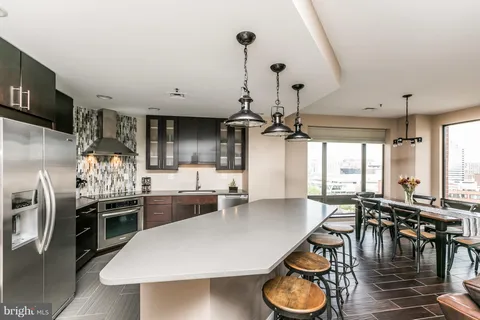 a kitchen with stainless steel appliances granite countertop a stove a refrigerator a dining table and chairs with wooden floor