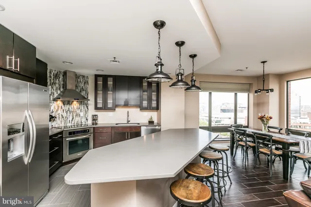 a kitchen with stainless steel appliances granite countertop a stove a refrigerator a dining table and chairs with wooden floor