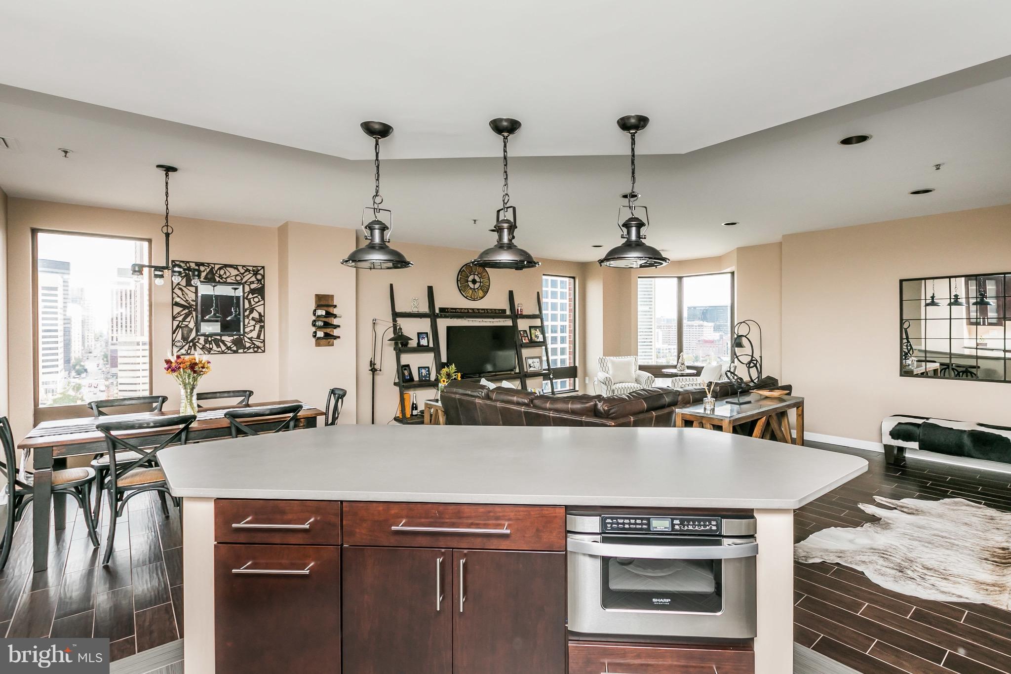 10 East Lee Street, Unit 1209 Baltimore, MD 21202 - Photo 11 of 38 a kitchen with a sink a stove and chairs