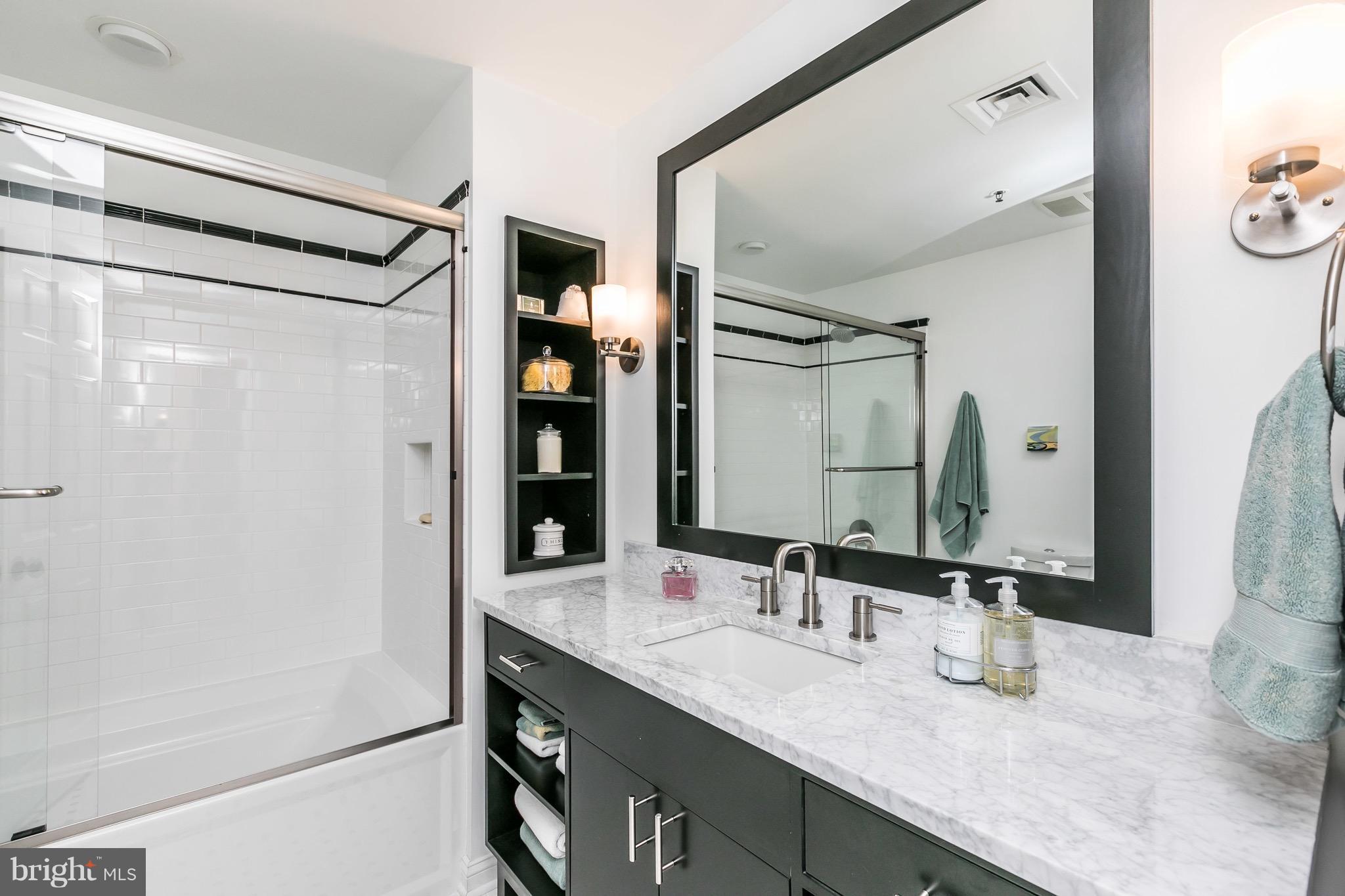 10 East Lee Street, Unit 1209 Baltimore, MD 21202 - Photo 26 of 38 a bathroom with a granite countertop sink and a mirror