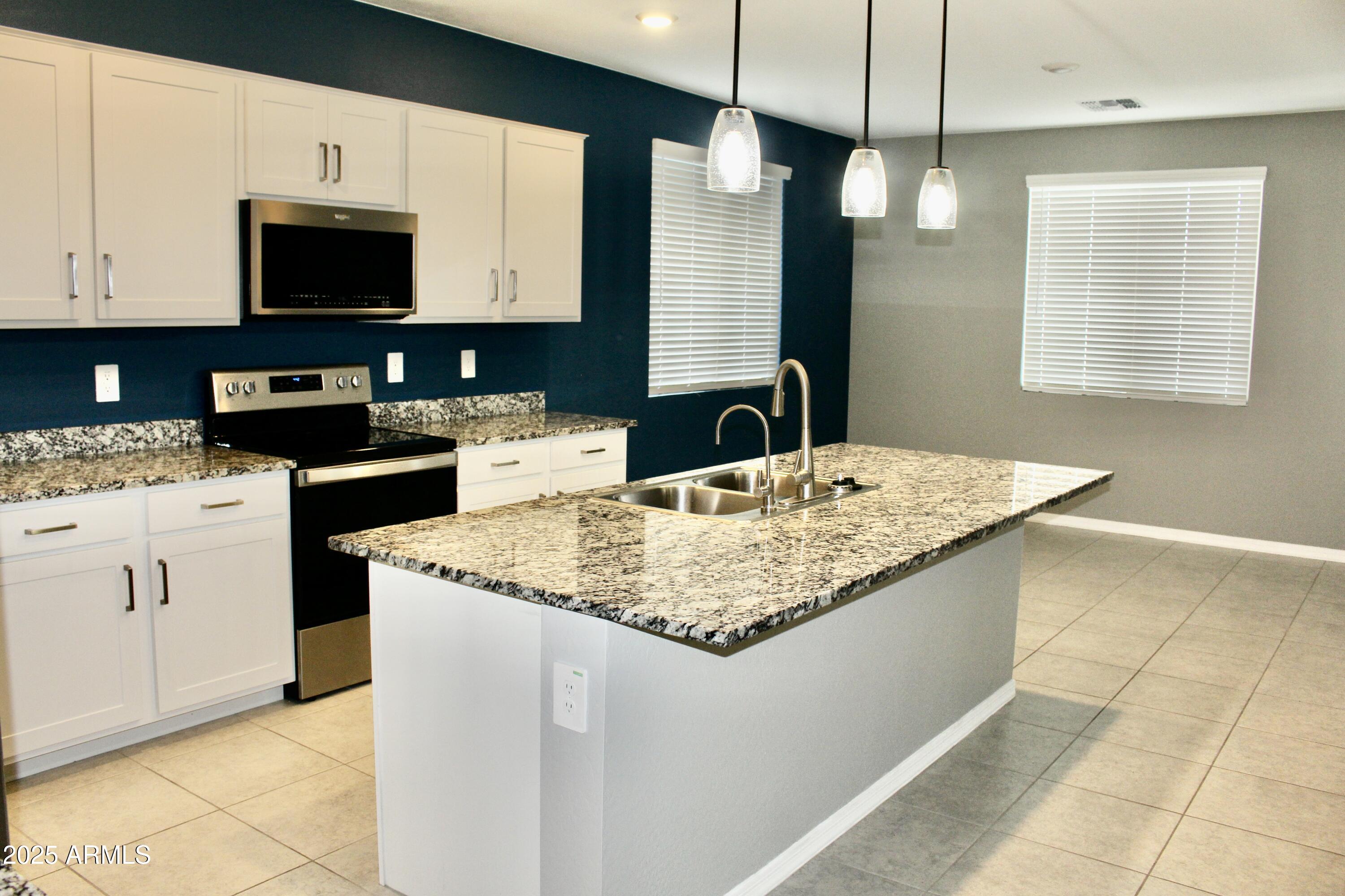 10805 West Levi Drive Tolleson, AZ 85353 - Photo 2 of 21 a kitchen with stainless steel appliances granite countertop a sink a stove and a microwave oven