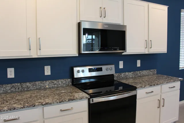 a kitchen with granite countertop white cabinets and black appliances