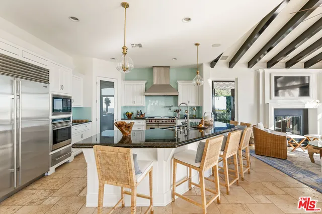 a kitchen with stainless steel appliances kitchen island granite countertop a refrigerator a stove a sink a dining table and chairs with wooden floor