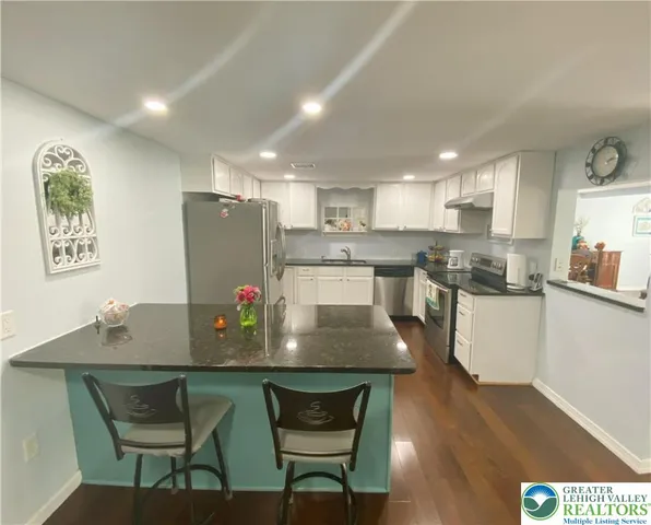 a kitchen with stainless steel appliances kitchen island granite countertop a table chairs and a refrigerator