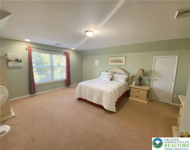 a spacious bedroom with a bed and dresser