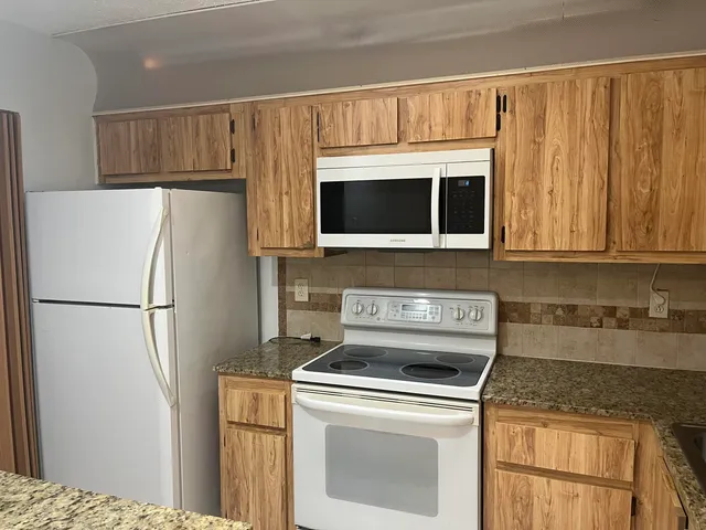 a kitchen with appliances a refrigerator and cabinets