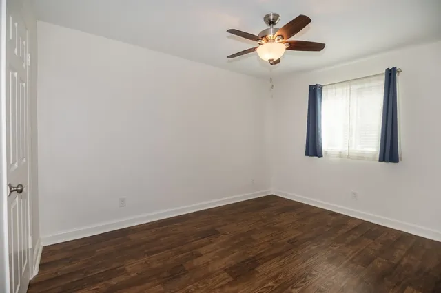 a view of an empty room with window and wooden floor