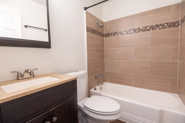 a bathroom with a granite countertop bathtub sink vanity mirror and toilet
