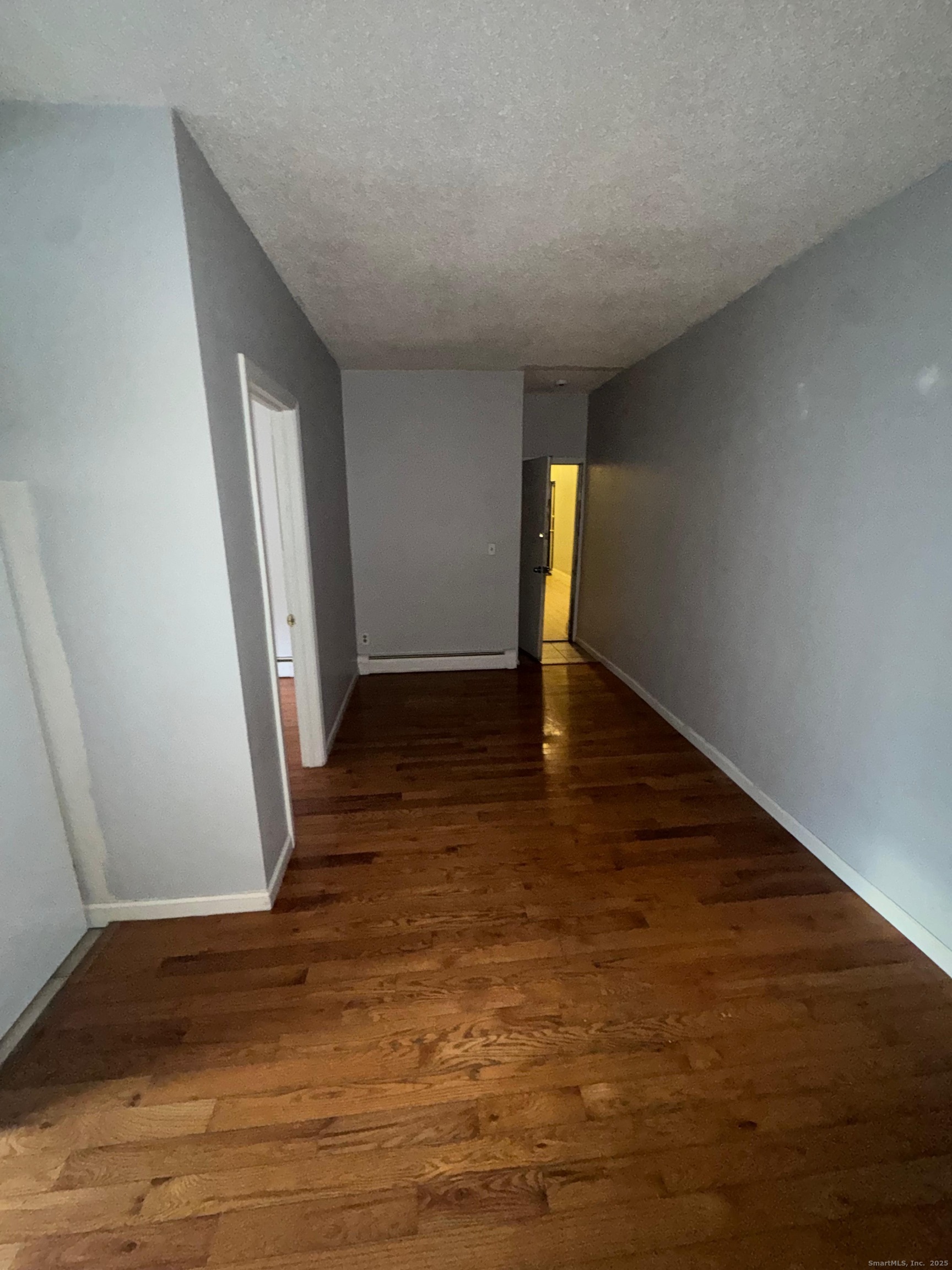 335 Wells Street, Unit W19 Bridgeport, CT 06606 - Photo 2 of 3 a view of an empty room with wooden floor and a window