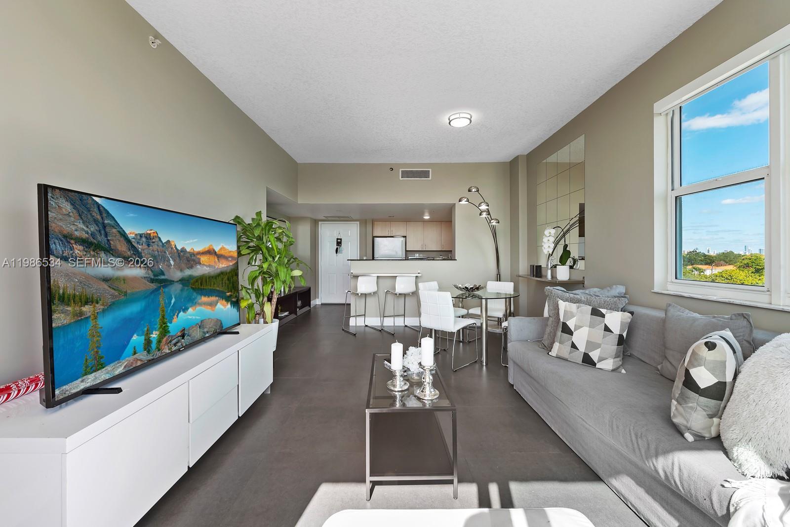 3000 Coral Way, Unit 416 Miami, FL 33145 - Photo 3 of 23 a living room with furniture a flat screen tv and a floor to ceiling window