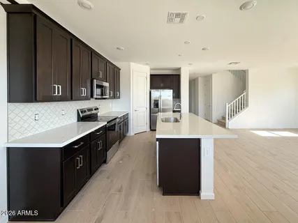 a large kitchen with stainless steel appliances a sink counter space and wooden floor