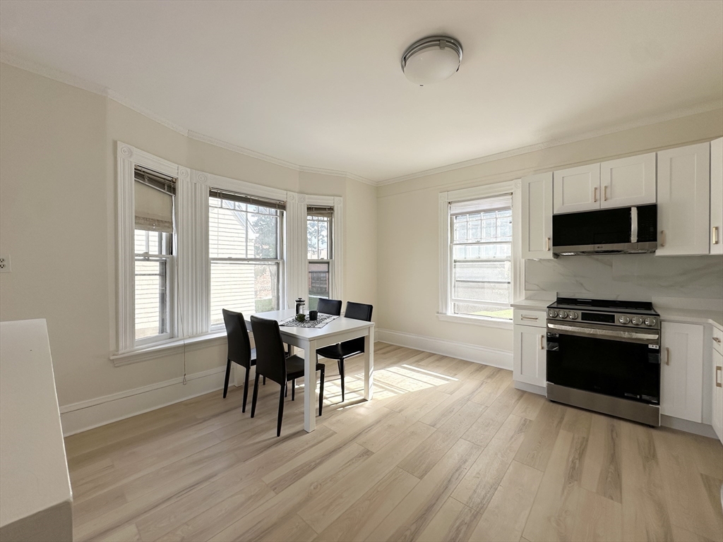 71 A Gardner Street, Unit 2 Boston, MA 02134 - Photo 4 of 13 a kitchen with stainless steel appliances granite countertop a stove top oven a sink dishwasher a dining table and chairs with wooden floor
