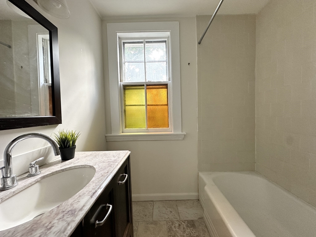 71 A Gardner Street, Unit 2 Boston, MA 02134 - Photo 8 of 13 a bathroom with a granite countertop sink and a bathtub