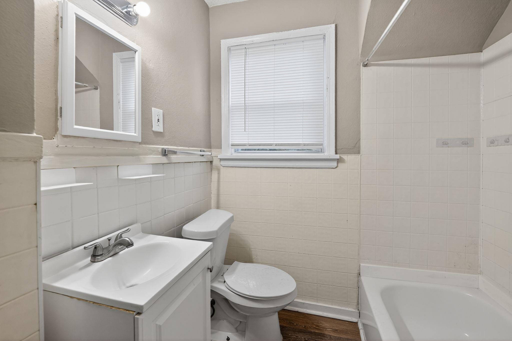 356 Hewlett Road Memphis, TN 38109 - Photo 26 of 30 Full bathroom featuring vanity, tile walls, dark wood finished floors, a wainscoted wall, and shower / bath combination