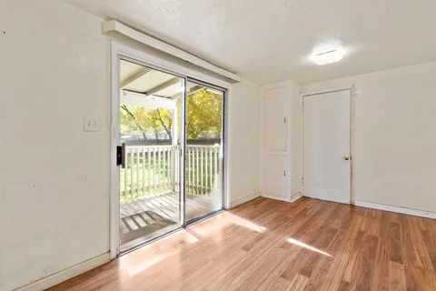 a view of empty room with wooden floor and fan