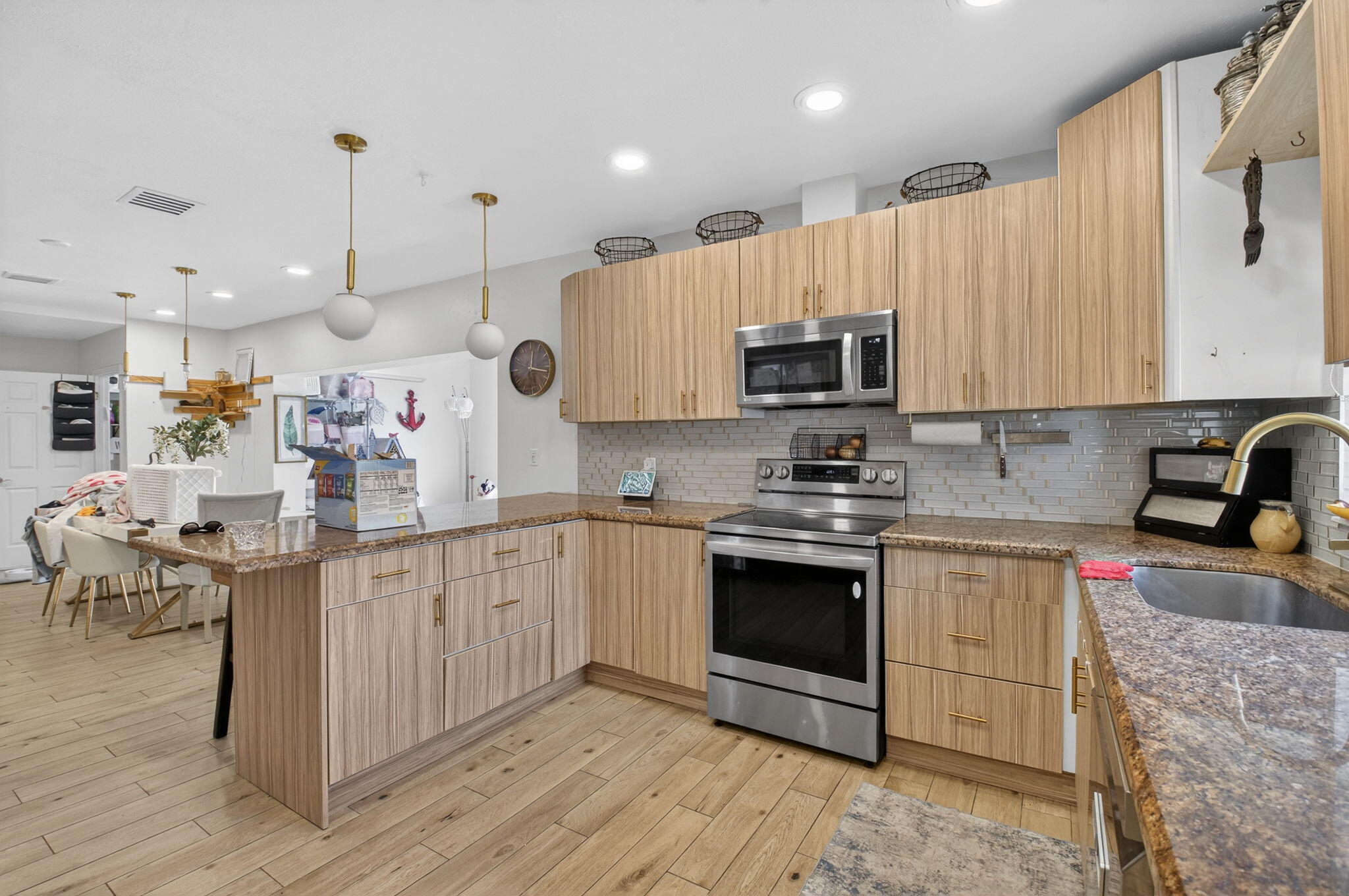 21724 Little Bear Way Boca Raton, FL 33428 - Photo 19 of 47 a kitchen with kitchen island granite countertop a stove top oven a sink dishwasher and white cabinets with wooden floor