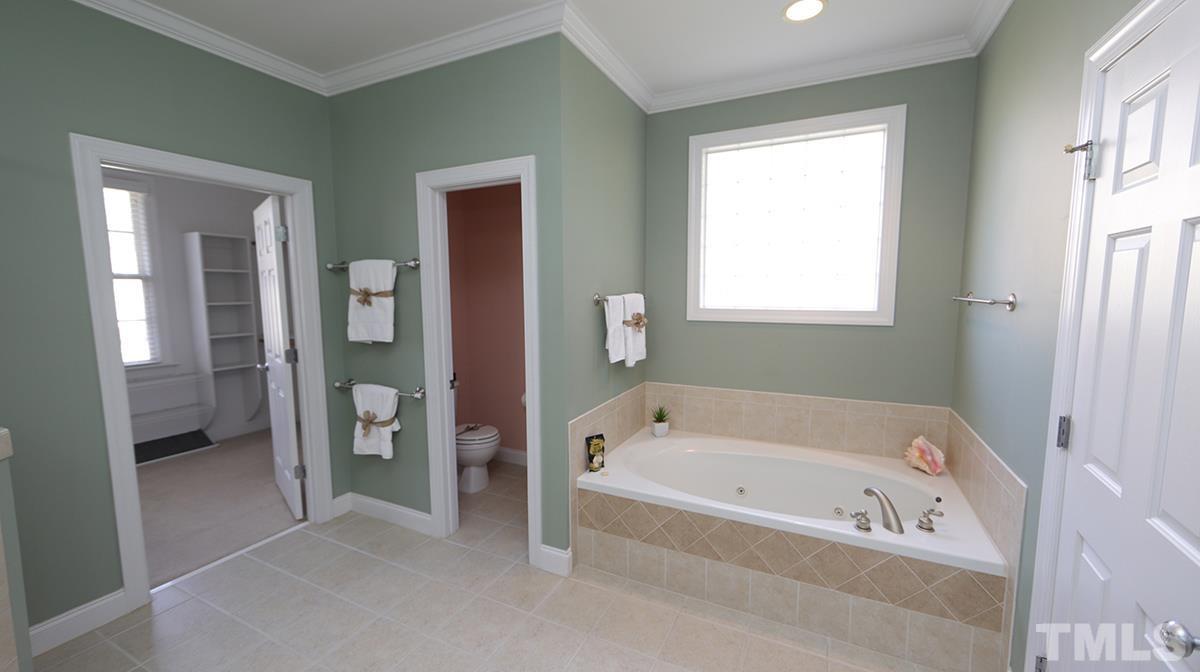 263 Waterville Street Raleigh, NC 27603 - Photo 14 of 18 a white bath tub sitting in a en suite bathroom next to a window