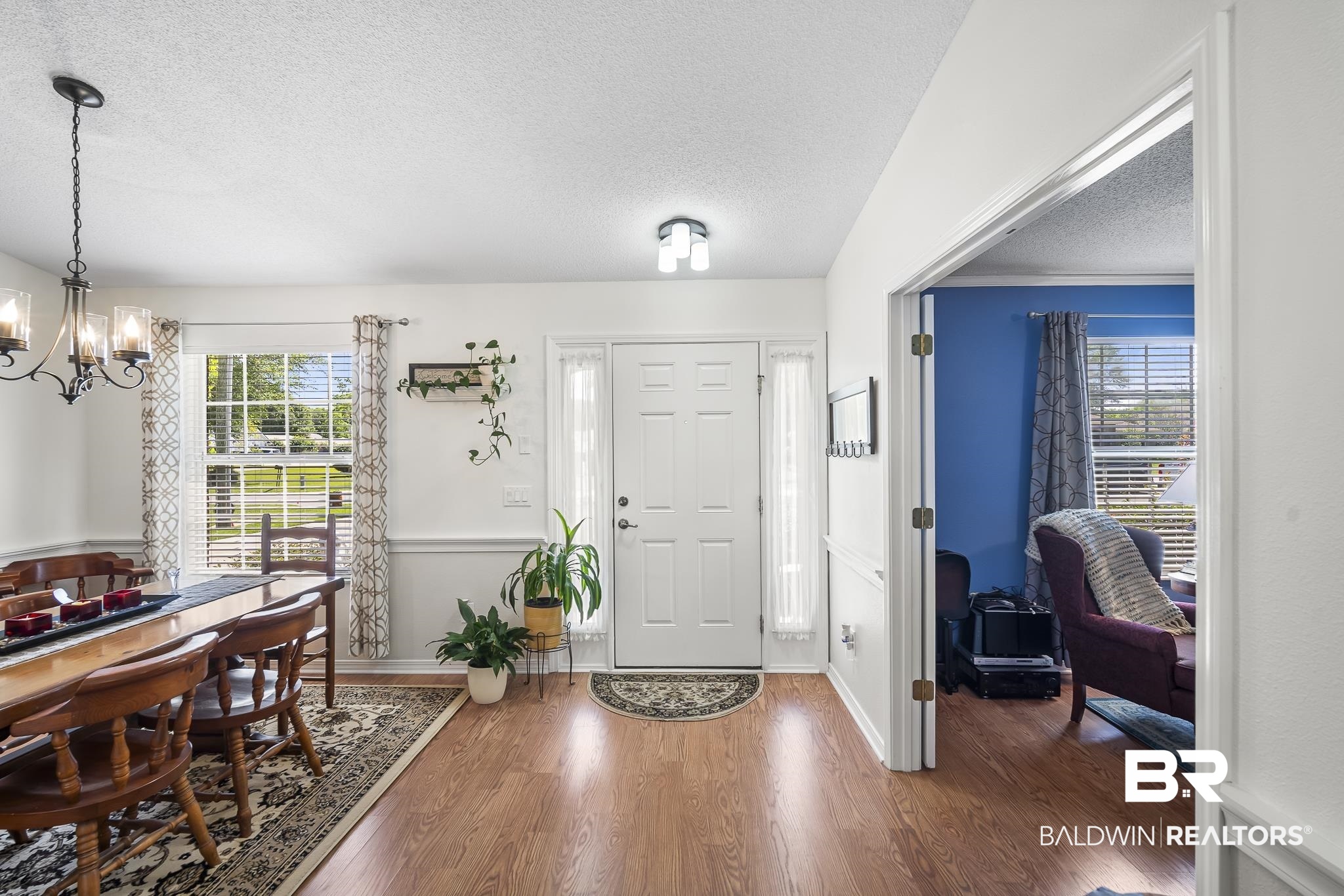 Entryway with a textured ceiling, a chandelier, healthy amount of natural light, wood finished floors, and baseboards