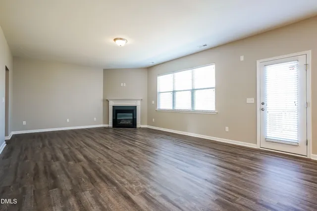 an empty room with wooden floor and fireplace