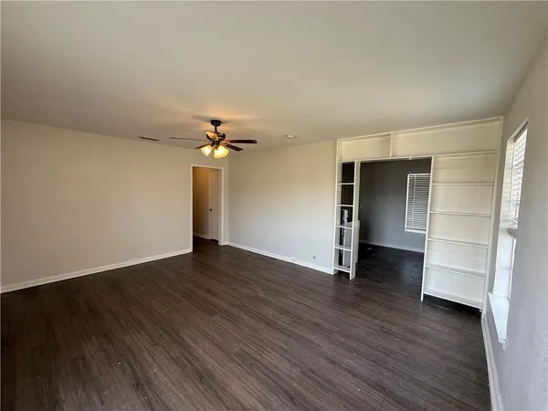 an empty room with wooden floor closet and windows