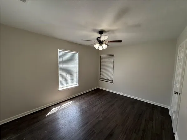 a view of an empty room with a window and wooden floor