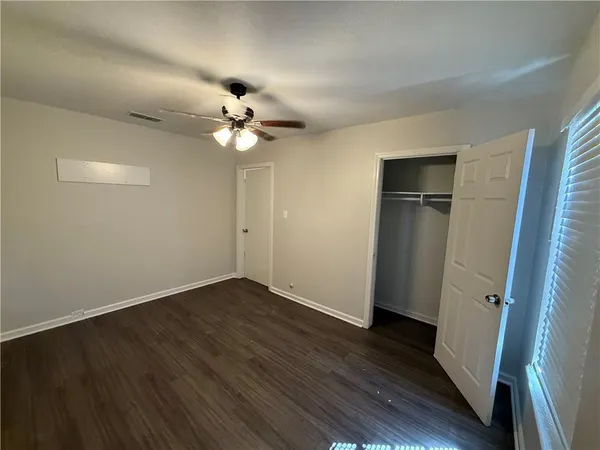 an empty room with wooden floor and ceiling fan