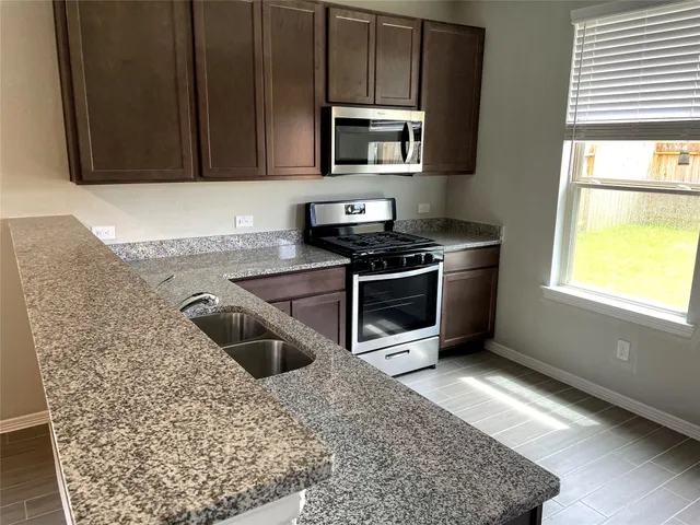 a kitchen with stainless steel appliances granite countertop a stove a sink and a microwave