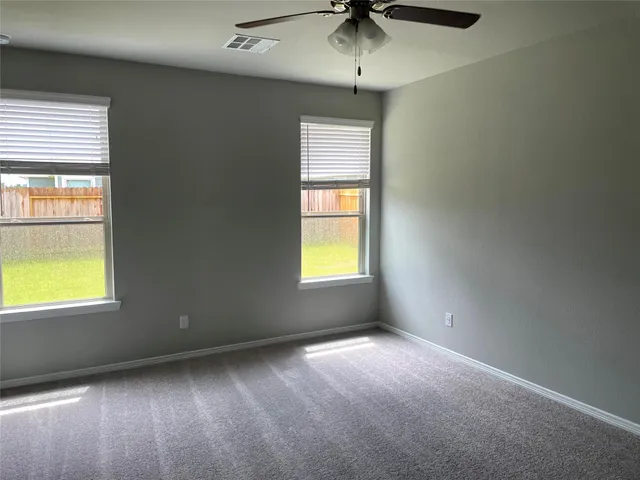 an empty room with a window and a ceiling fan