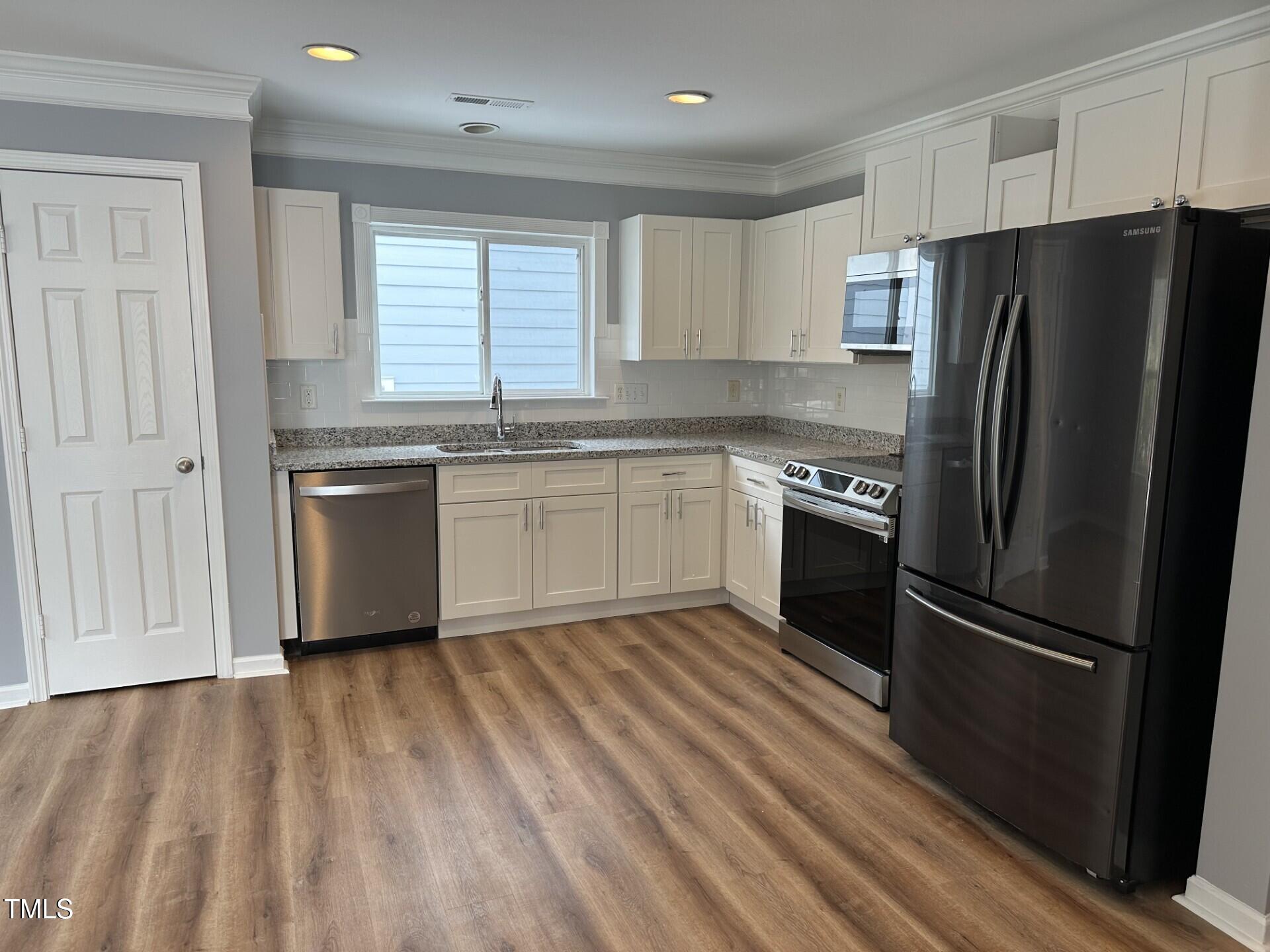 336 New Milford Road Cary, NC 27519 - Photo 16 of 53 a kitchen with granite countertop stainless steel appliances a refrigerator cabinets and wooden floor