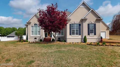 a front view of a house with a large tree