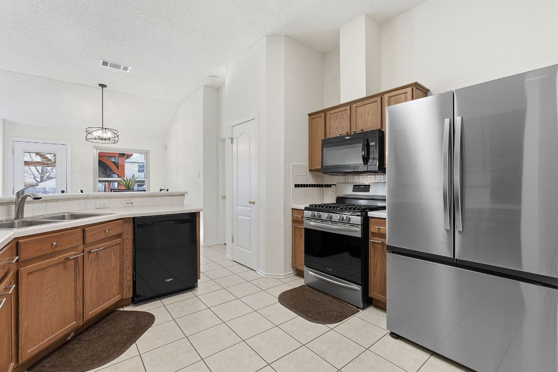 1203 Crossvine Way Pflugerville, TX 78660 - Photo 7 of 22 a kitchen with stainless steel appliances a refrigerator sink and microwave