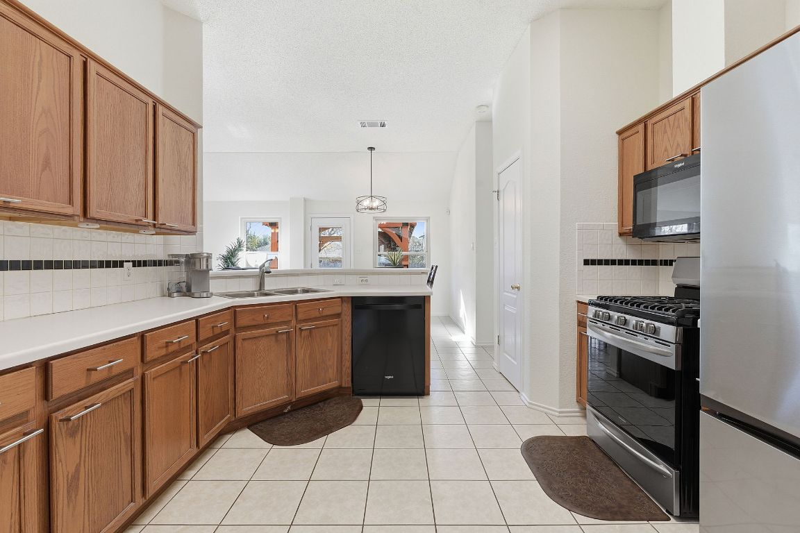 1203 Crossvine Way Pflugerville, TX 78660 - Photo 8 of 22 a kitchen with stainless steel appliances granite countertop a stove a sink and a refrigerator