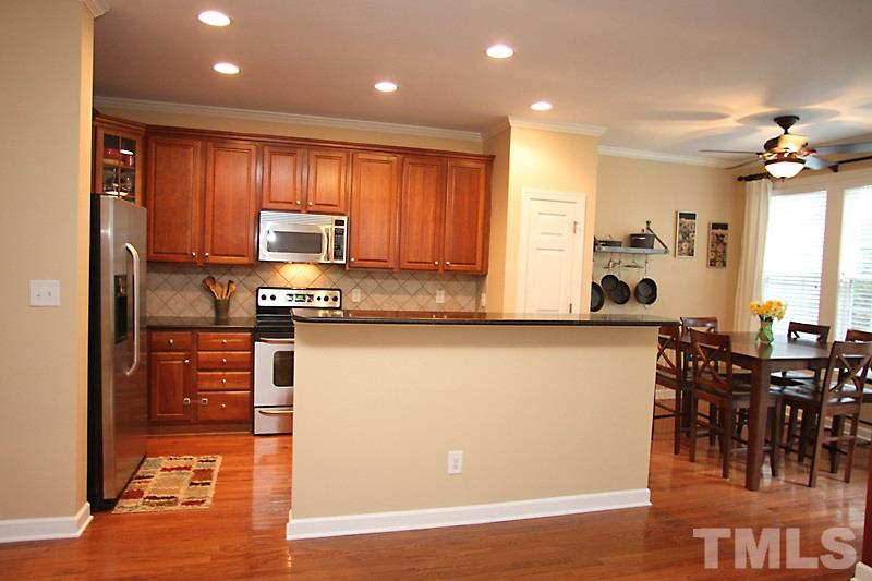 3520 Edgemont Drive Raleigh, NC 27612 - Photo 7 of 12 a kitchen with stainless steel appliances granite countertop a stove top oven a sink a dining table and chairs with wooden floor