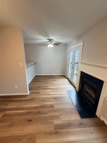a view of an empty room with wooden floor fireplace and a window