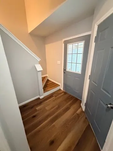 a view of an empty room with wooden floor and stairs
