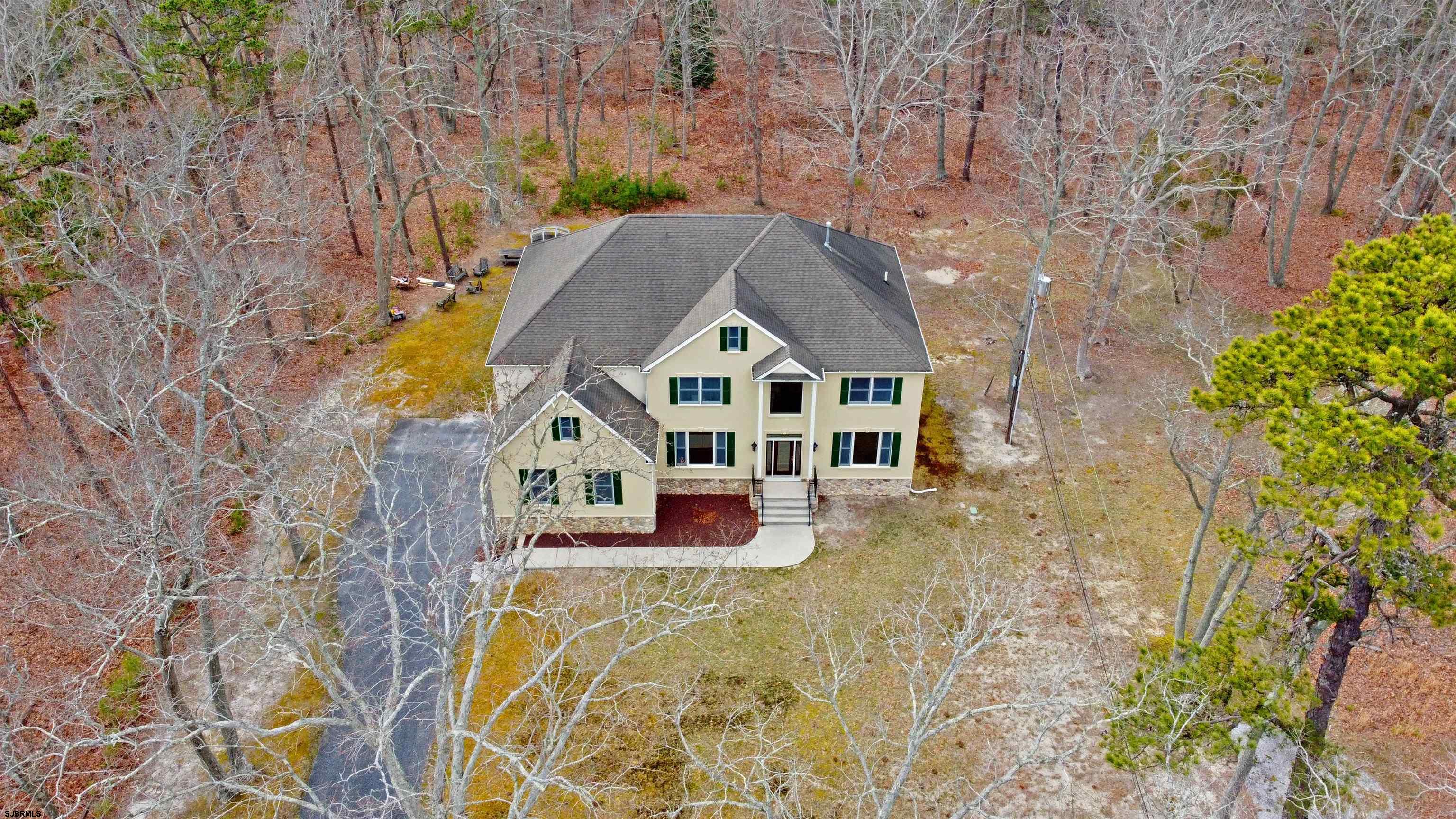 a front view of a house with large trees and plants