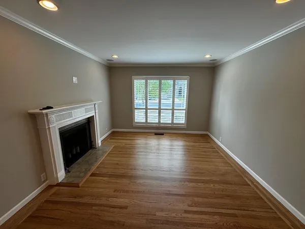 a view of an empty room with wooden floor fireplace and a window