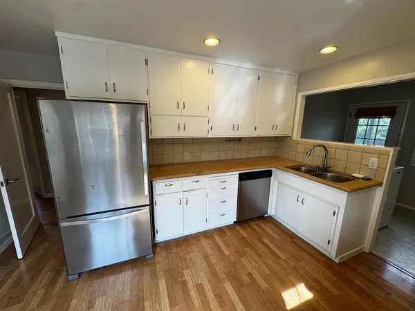 a kitchen with granite countertop white cabinets and stainless steel appliances