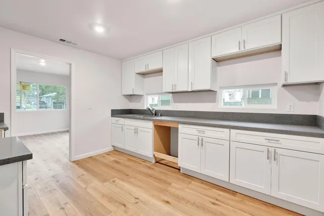 a kitchen with granite countertop white cabinets and white appliances with wooden floor