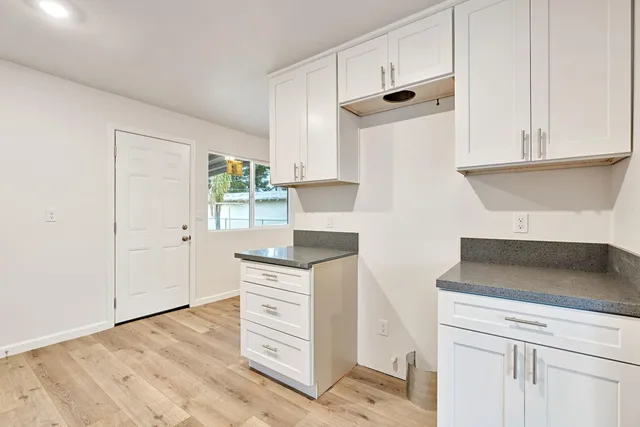 a kitchen with granite countertop white cabinets and white appliances