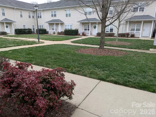 a view of a white house with a big yard and potted plants