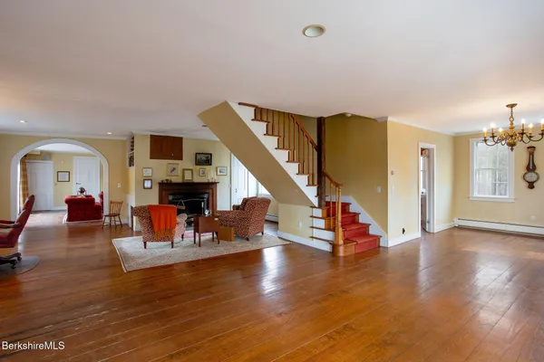 a large white kitchen with granite countertop a stove a sink a refrigerator and white cabinets with wooden floor