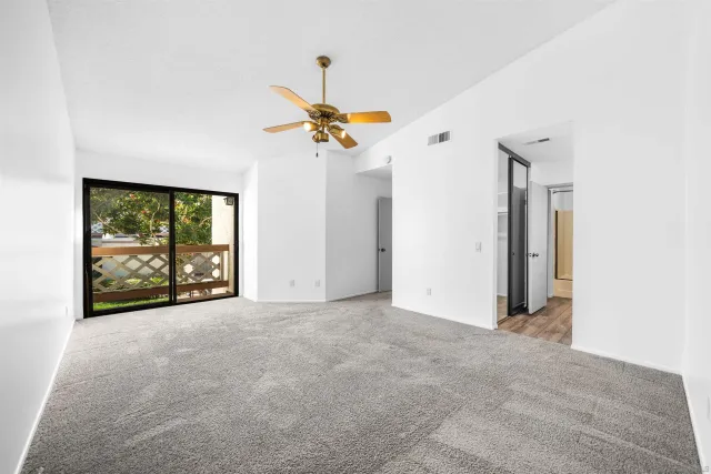 an empty room with windows and a chandelier fan