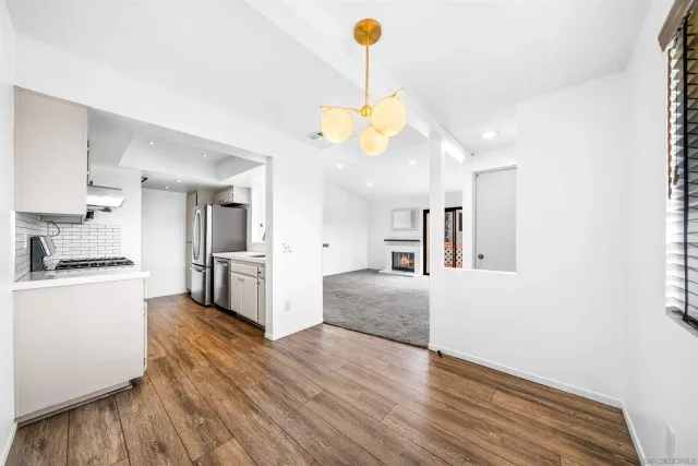 a kitchen with stainless steel appliances kitchen island granite countertop a stove a sink a refrigerator and white cabinets with wooden floor