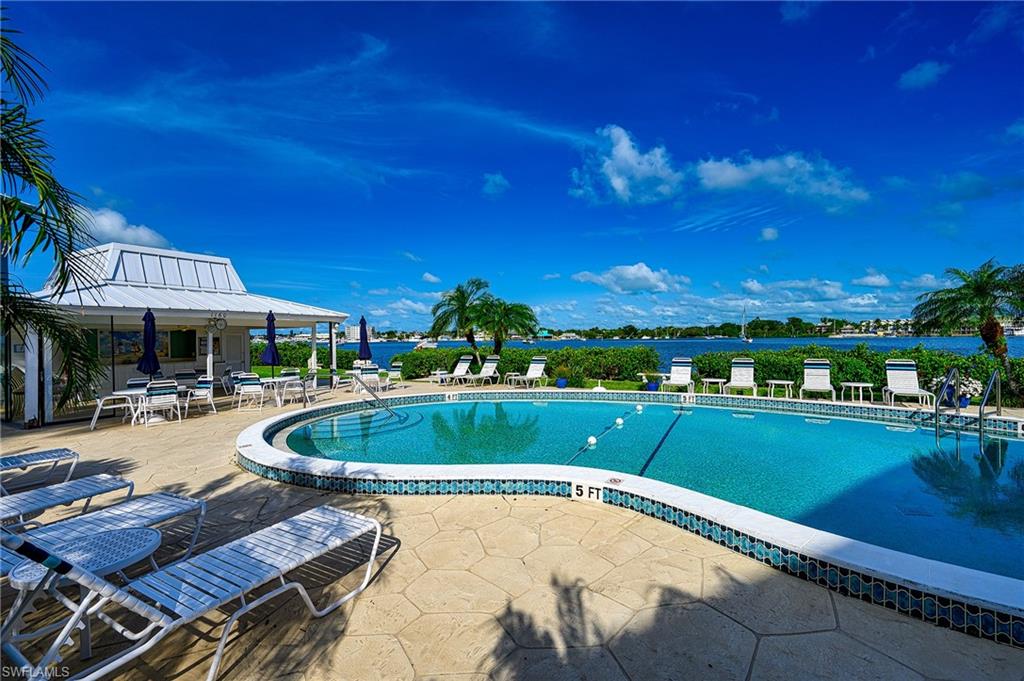 1280 Blue Point Avenue, Unit C30 Naples, FL 34102 - Photo 20 of 24 a view of a swimming pool and lounge chairs