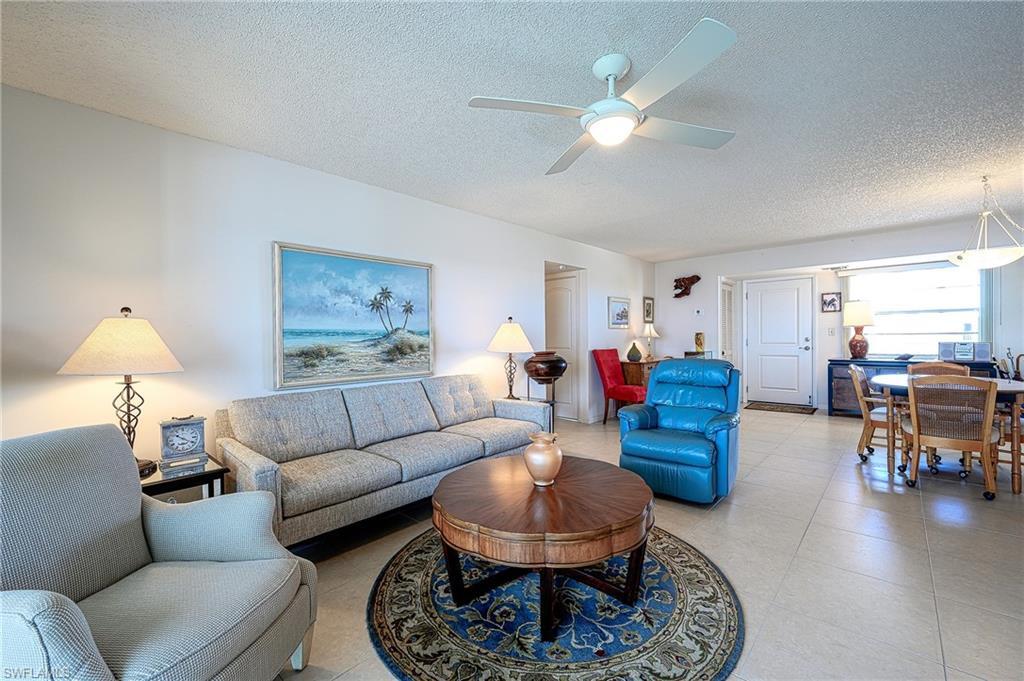 1280 Blue Point Avenue, Unit C30 Naples, FL 34102 - Photo 4 of 24 a living room with furniture a fireplace and a chandelier